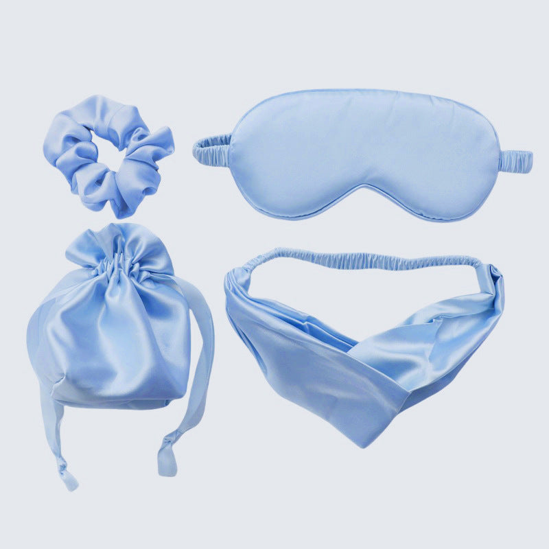 Set of blue satin items including a sleep mask, headband, pouch, and scrunchie
